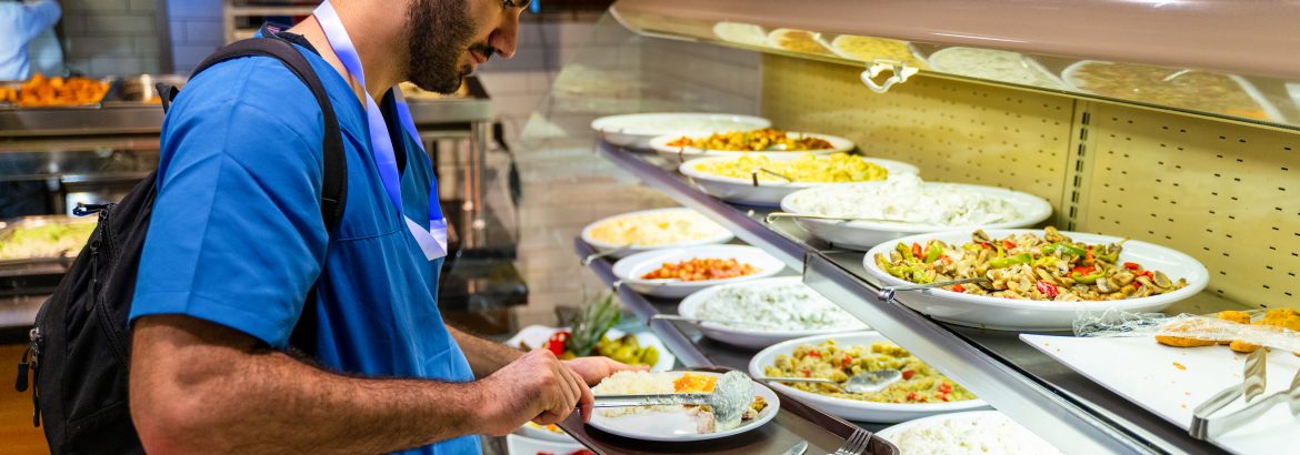 Man in Medical Scrubs Eating at a Buffet Style Cafeteria