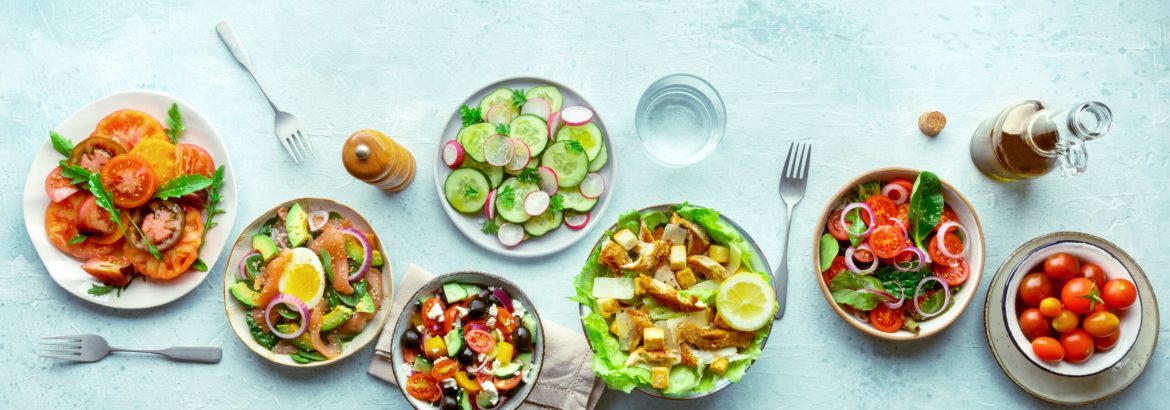 Fresh salads, overhead flat lay shot of an assortment. Variety of plates and bowls with green vegetables. Healthy food, top shot, with copy space