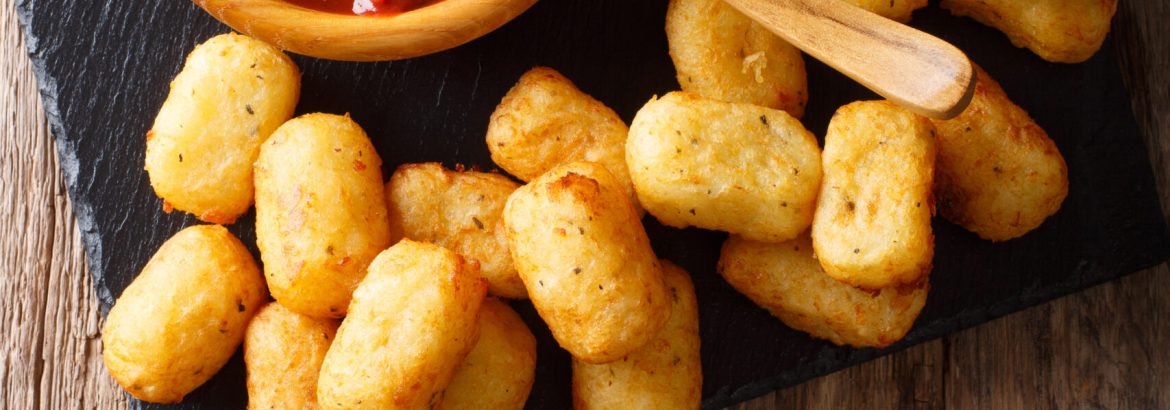 close up of rustic golden potato tater tots and ketchup on the table. Vertical top view from above